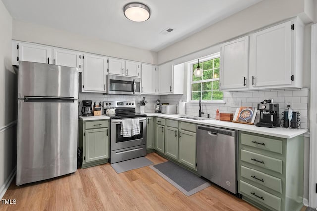 411 Buxton St, Durham, NC 27713 - kitchen with green cabinetry, appliances with stainless steel finishes, white cabinetry, light countertops, and decorative backsplash
