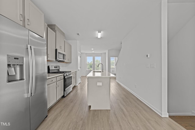 447 N Fisher St, Raleigh, NC 27610 - kitchen with stainless steel appliances, a sink, light wood-style floors, a kitchen island with sink, and light countertops