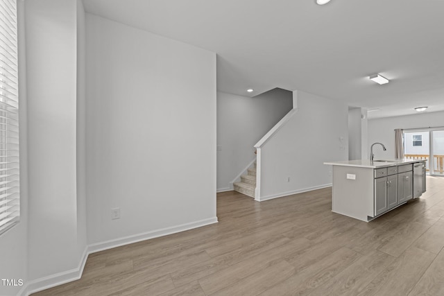 447 N Fisher St, Raleigh, NC 27610 - kitchen featuring a sink, light wood-type flooring, light countertops, baseboards, and a kitchen island with sink