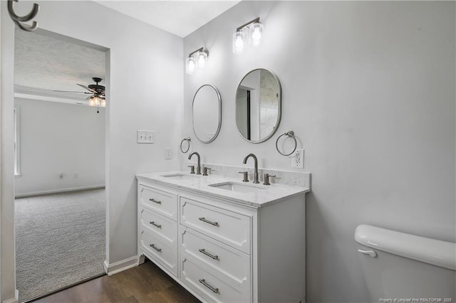 120 Wood Valley Ln, Raeford, NC 29376 - bathroom with a ceiling fan, toilet, double vanity, wood finished floors, and baseboards