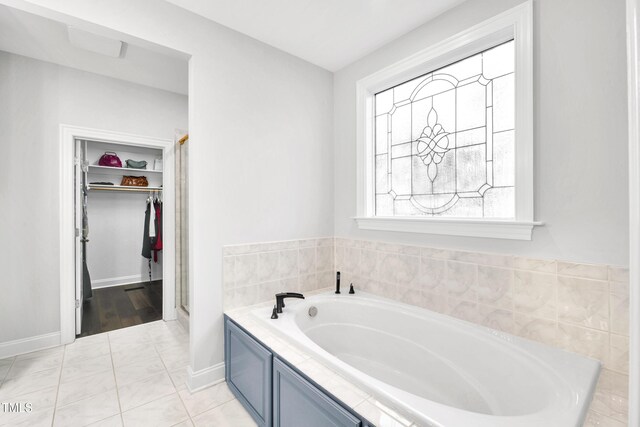 390 Lake Magnolia Way, Smithfield, NC 27577 - bathroom featuring a garden tub, a spacious closet, baseboards, and a stall shower