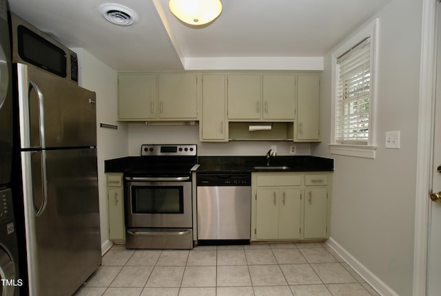 1908 Smallwood Dr, Raleigh, NC 27605 - kitchen featuring appliances with stainless steel finishes, a sink, dark countertops, baseboards, and cream cabinets