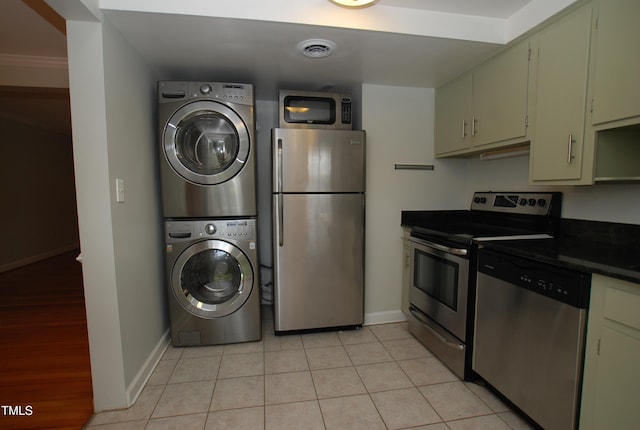 1908 Smallwood Dr, Raleigh, NC 27605 - kitchen with appliances with stainless steel finishes, stacked washing machine and dryer, baseboards, dark countertops, and light tile patterned floors
