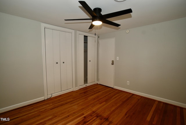 1908 Smallwood Dr, Raleigh, NC 27605 - unfurnished bedroom with wood finished floors, baseboards, a ceiling fan, and two closets