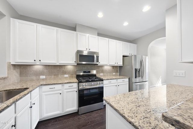 684 Wickham Ridge Rd, Apex, NC 27539 - kitchen with stainless steel appliances, arched walkways, white cabinets, dark wood-style floors, and recessed lighting