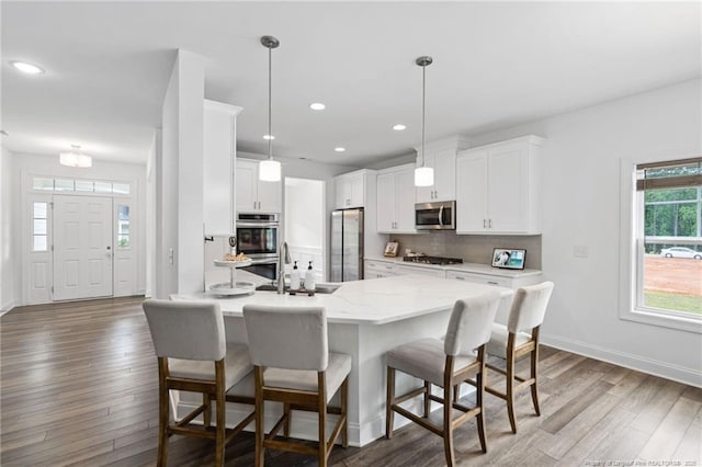 25 Vast View Way, Youngsville, NC 27596 - kitchen with appliances with stainless steel finishes, wood finished floors, a kitchen bar, decorative backsplash, and recessed lighting