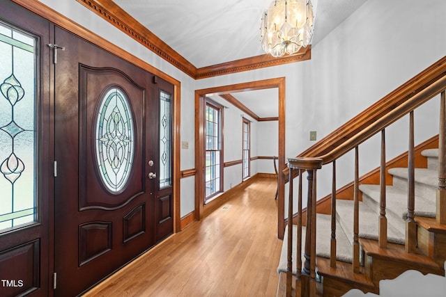 221 Jansmith Ln, Raleigh, NC 27615 - entrance foyer featuring crown molding, a chandelier, light wood-style flooring, stairway, and plenty of natural light
