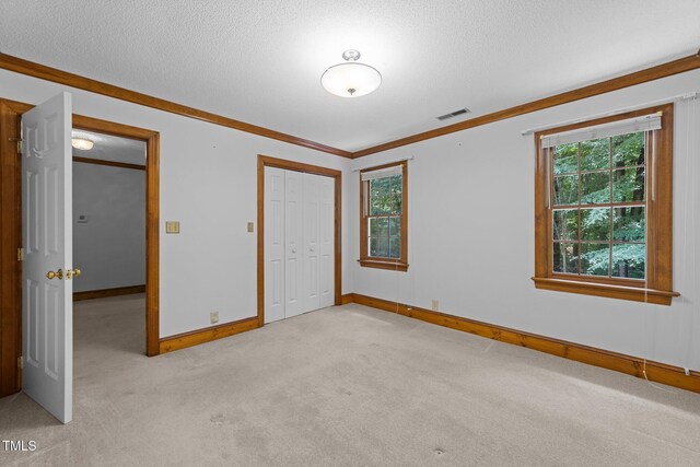 221 Jansmith Ln, Raleigh, NC 27615 - unfurnished bedroom featuring light carpet, baseboards, multiple windows, a closet, and a textured ceiling