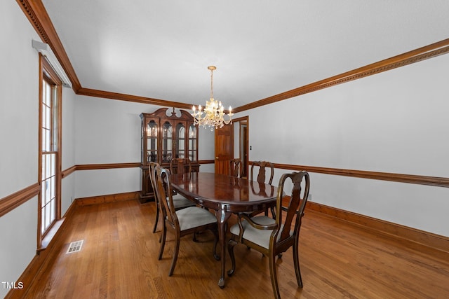 221 Jansmith Ln, Raleigh, NC 27615 - dining area with a chandelier, baseboards, wood finished floors, and ornamental molding