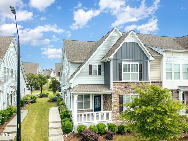 921 Rosepine Dr, Cary, NC 27519 - view of front of home featuring board and batten siding, stone siding, a front yard, roof with shingles, and a porch