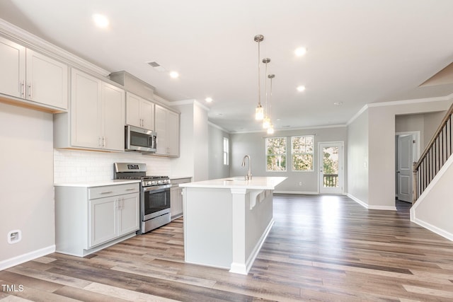 591 Traditions Grande Blvd, Wake Forest, NC 27587 - kitchen with appliances with stainless steel finishes, an island with sink, light wood-style floors, light countertops, and ornamental molding