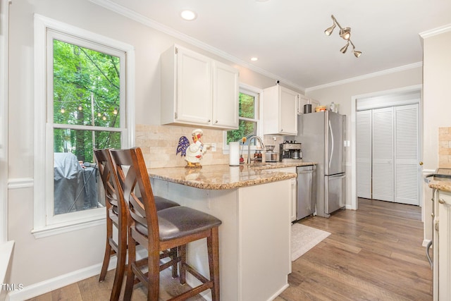 1426 Cedar Branch Ct, Wake Forest, NC 27587 - kitchen featuring appliances with stainless steel finishes, healthy amount of natural light, white cabinets, ornamental molding, and backsplash