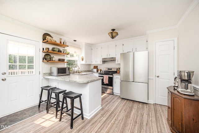 701 Creekside Dr, Clayton, NC 27520 - kitchen with appliances with stainless steel finishes, under cabinet range hood, a peninsula, crown molding, and light wood-style flooring