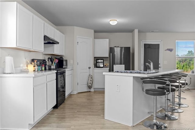 259 Desert Orchid Cir, Raeford, NC 28376 - kitchen featuring freestanding refrigerator, electric range, under cabinet range hood, a kitchen bar, and white cabinets