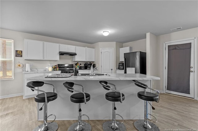 259 Desert Orchid Cir, Raeford, NC 28376 - kitchen with black electric range, under cabinet range hood, freestanding refrigerator, white cabinets, and a kitchen breakfast bar