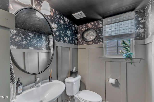 6509 Conaway Ct, Wake Forest, NC 27587 - bathroom featuring wallpapered walls, wainscoting, a sink, toilet, and a decorative wall
