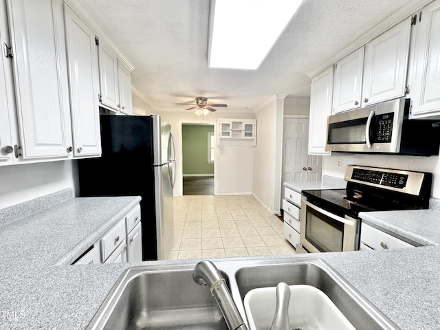 322 S Dixon Ave, Cary, NC 27511 - kitchen featuring stainless steel appliances, light tile patterned floors, white cabinetry, a textured ceiling, and ornamental molding
