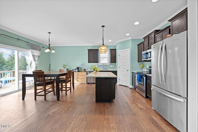 224 Swann Trl, Clayton, NC 27527 - kitchen with appliances with stainless steel finishes, dark brown cabinetry, a center island, ornamental molding, and decorative light fixtures