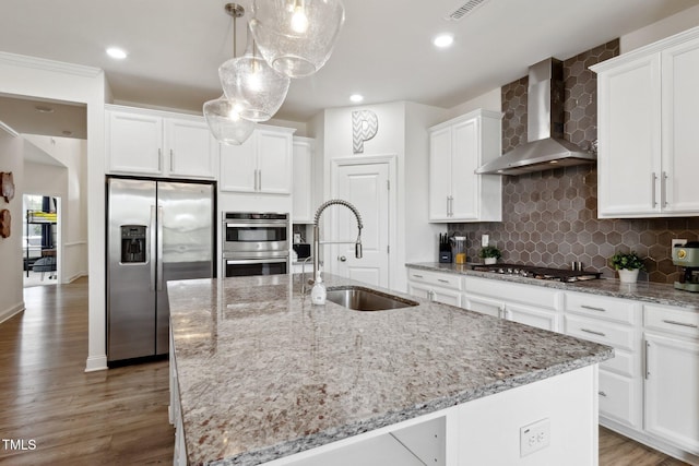 404 Porterfield Dr, Youngsville, NC 27596 - kitchen featuring appliances with stainless steel finishes, wall chimney exhaust hood, an island with sink, white cabinets, and light stone countertops