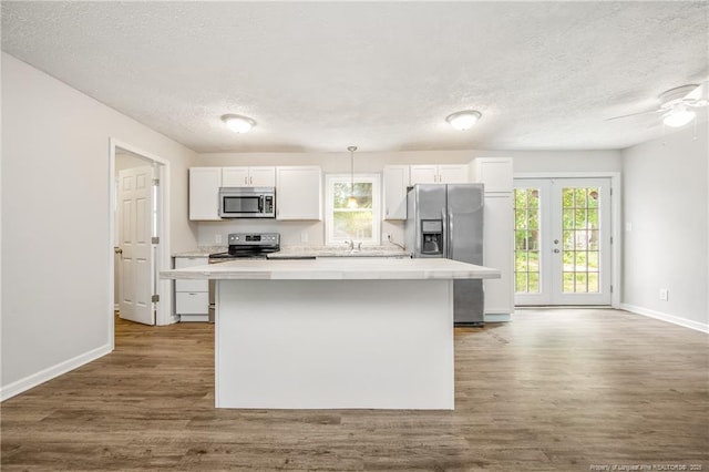6313 Belle Terre Ct, Fayetteville, NC 28304 - kitchen featuring appliances with stainless steel finishes, a textured ceiling, a center island, white cabinetry, and dark wood finished floors
