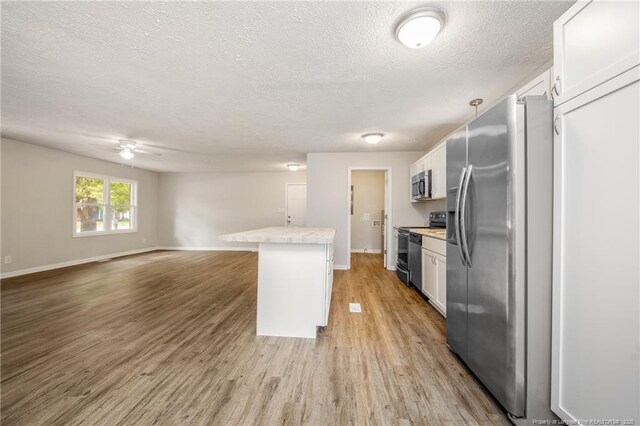 6313 Belle Terre Ct, Fayetteville, NC 28304 - kitchen with stainless steel appliances, light countertops, light wood-style flooring, open floor plan, and a textured ceiling