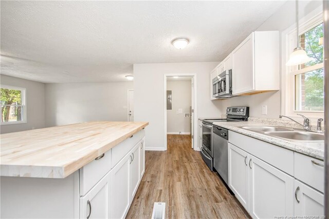 6313 Belle Terre Ct, Fayetteville, NC 28304 - kitchen with wood counters, stainless steel appliances, a sink, light wood-style floors, and white cabinets