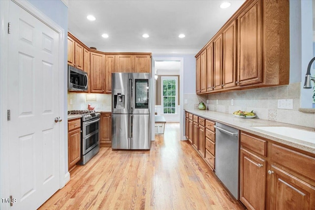 1128 Neuse Ridge Dr, Clayton, NC 27527 - kitchen with appliances with stainless steel finishes, light wood-type flooring, brown cabinetry, tasteful backsplash, and recessed lighting