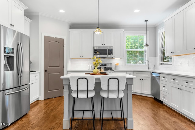 118 Fox Run Ct, Durham, NC 27705 - kitchen with stainless steel appliances, a sink, ornamental molding, a kitchen island, and a kitchen bar