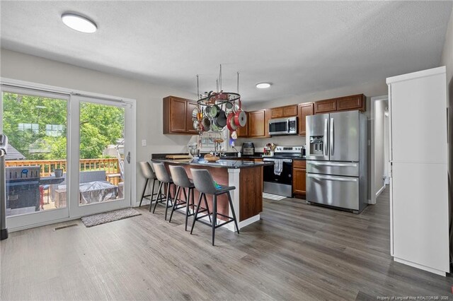 701 Dandridge Dr, Fayetteville, NC 28304 - kitchen featuring appliances with stainless steel finishes, dark countertops, a kitchen bar, dark wood finished floors, and a peninsula