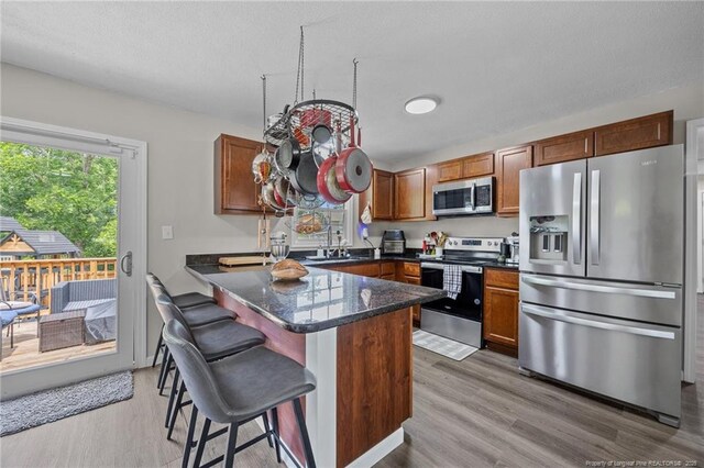 701 Dandridge Dr, Fayetteville, NC 28304 - kitchen with appliances with stainless steel finishes, light wood-style floors, a kitchen breakfast bar, and brown cabinets