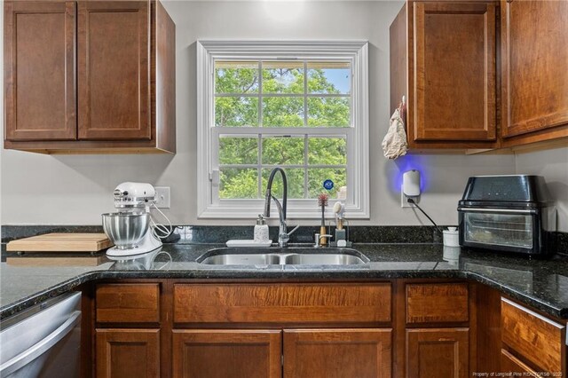701 Dandridge Dr, Fayetteville, NC 28304 - kitchen featuring stainless steel dishwasher, a sink, dark stone counters, and brown cabinets