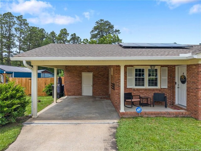 701 Dandridge Dr, Fayetteville, NC 28304 - ranch-style house with covered porch, concrete driveway, roof mounted solar panels, brick siding, and roof with shingles