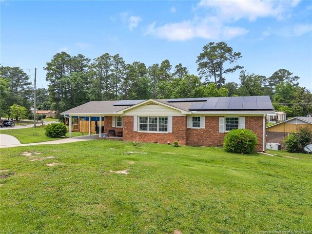 701 Dandridge Dr, Fayetteville, NC 28304 - ranch-style house with a front lawn, roof mounted solar panels, brick siding, and an attached carport