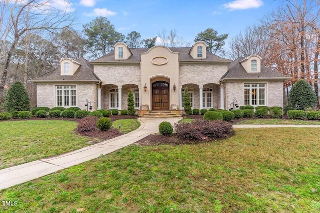 166 Bonica Creek Dr, Garner, NC 27529 - french provincial home featuring stone siding, a front yard, and brick siding