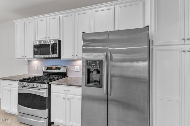 10511 Sablewood Dr Unit 107, Raleigh, NC 27617 - kitchen with appliances with stainless steel finishes, dark stone countertops, white cabinetry, and decorative backsplash