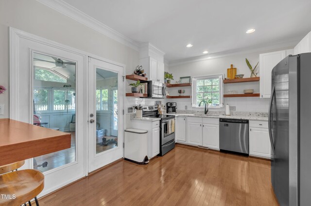 1905 Indianwood Ct, Raleigh, NC 27604 - kitchen with appliances with stainless steel finishes, open shelves, crown molding, white cabinets, and light wood-type flooring