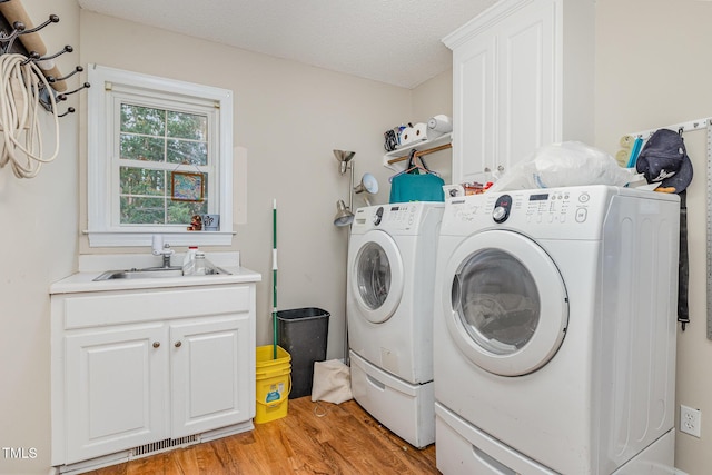 110 Windyfield Dr, Goldsboro, NC 27530 - laundry room with washing machine and dryer, cabinet space, light wood-style floors, and a textured ceiling