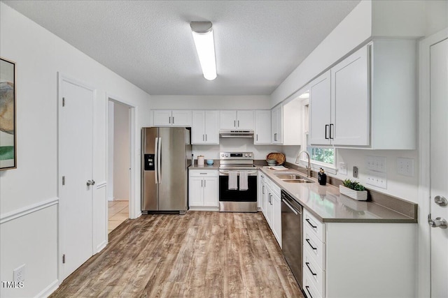1209 Lochcarron Ln, Cary, NC 27511 - kitchen with appliances with stainless steel finishes, a sink, white cabinetry, light wood-style flooring, and a textured ceiling