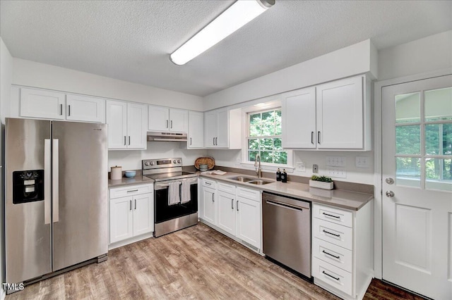 1209 Lochcarron Ln, Cary, NC 27511 - kitchen featuring stainless steel appliances, a sink, under cabinet range hood, light wood-style floors, and white cabinetry