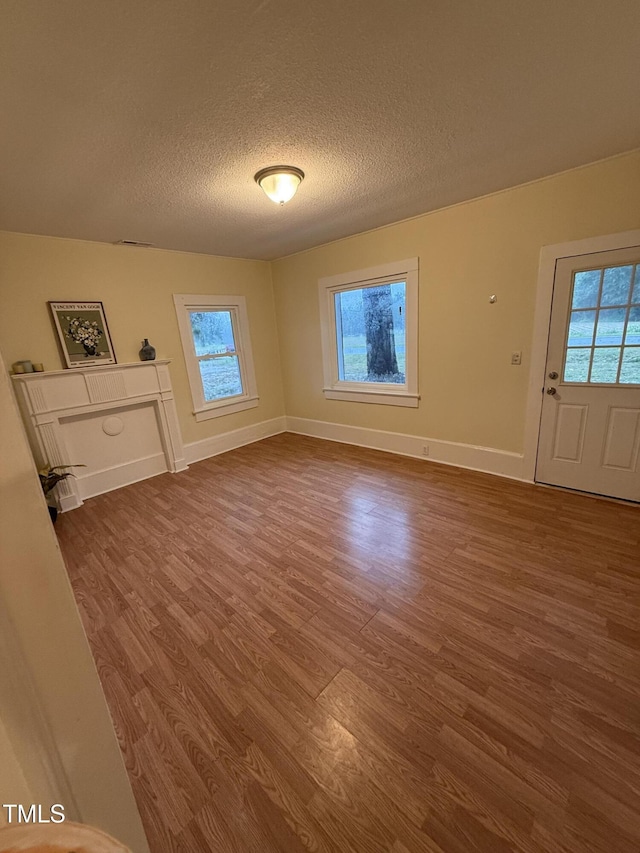 340 Jones Rd, Newton Grove, NC 28366 - unfurnished living room with dark wood-style flooring, healthy amount of natural light, a textured ceiling, and baseboards