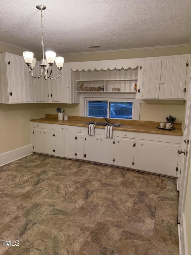 340 Jones Rd, Newton Grove, NC 28366 - kitchen featuring a textured ceiling, white cabinets, a chandelier, baseboards, and crown molding