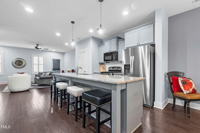 1448 Big Falls Dr, Wendell, NC 27591 - kitchen with stainless steel appliances, dark wood-style floors, baseboards, a breakfast bar, and recessed lighting