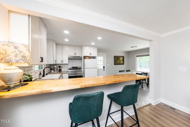 2968 Tram Rd, Fuquay Varina, NC 27526 - kitchen featuring freestanding refrigerator, stainless steel range with electric stovetop, butcher block countertops, a sink, and a peninsula