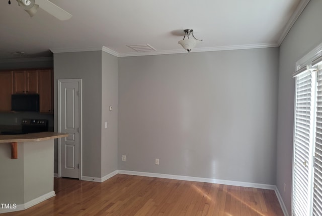 4202 Cherry Blossom Cir, Durham, NC 27713 - kitchen featuring stove, light wood-style floors, black microwave, crown molding, and baseboards