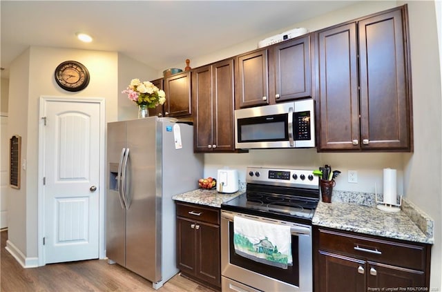 1865 John B Carter Rd, Fayetteville, NC 28312 - kitchen featuring appliances with stainless steel finishes, light wood finished floors, dark brown cabinetry, light stone counters, and recessed lighting
