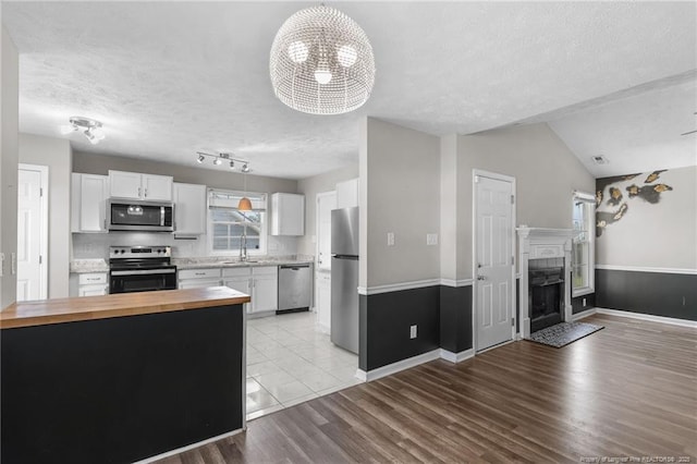 1419 Acacia Dr, Fayetteville, NC 28314 - kitchen with appliances with stainless steel finishes, butcher block counters, a textured ceiling, white cabinets, and a sink
