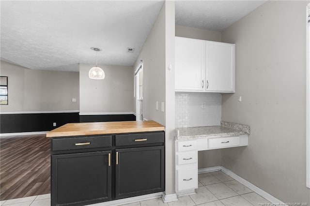 1419 Acacia Dr, Fayetteville, NC 28314 - kitchen with white cabinetry, backsplash, baseboards, decorative light fixtures, and wooden counters