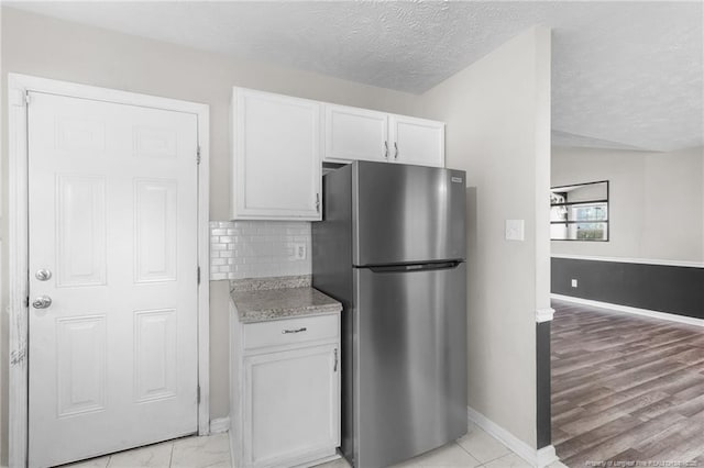 1419 Acacia Dr, Fayetteville, NC 28314 - kitchen with freestanding refrigerator, white cabinets, baseboards, a textured ceiling, and decorative backsplash
