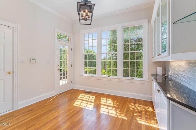 218 W Barbee Chapel Rd, Chapel Hill, NC 27517 - unfurnished dining area with baseboards, light wood finished floors, a chandelier, and crown molding