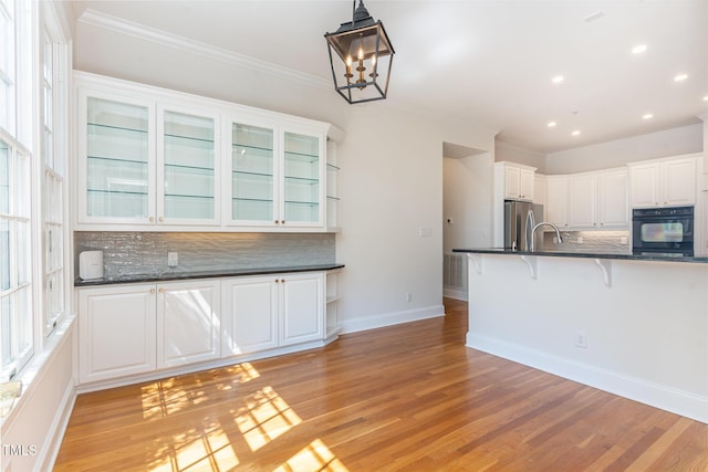 218 W Barbee Chapel Rd, Chapel Hill, NC 27517 - kitchen with black oven, freestanding refrigerator, backsplash, a breakfast bar area, and light wood-type flooring
